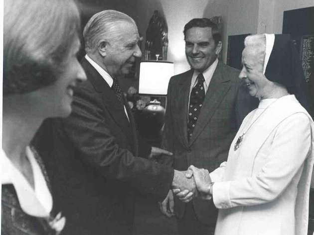 Sister Trinita Flood, O.P., shakes hands with Shepard Broad at her inauguration reception